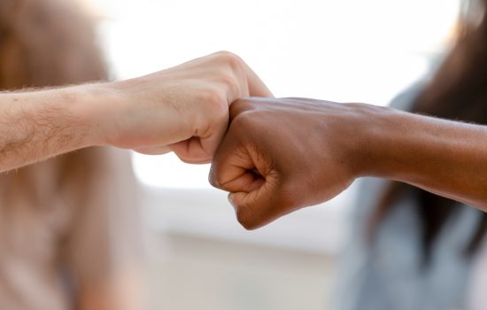 Diverse male hands giving fist bump, two african american and caucasian men greeting as business partnership, multiracial people friends culture, power trust respect support concept, close up view